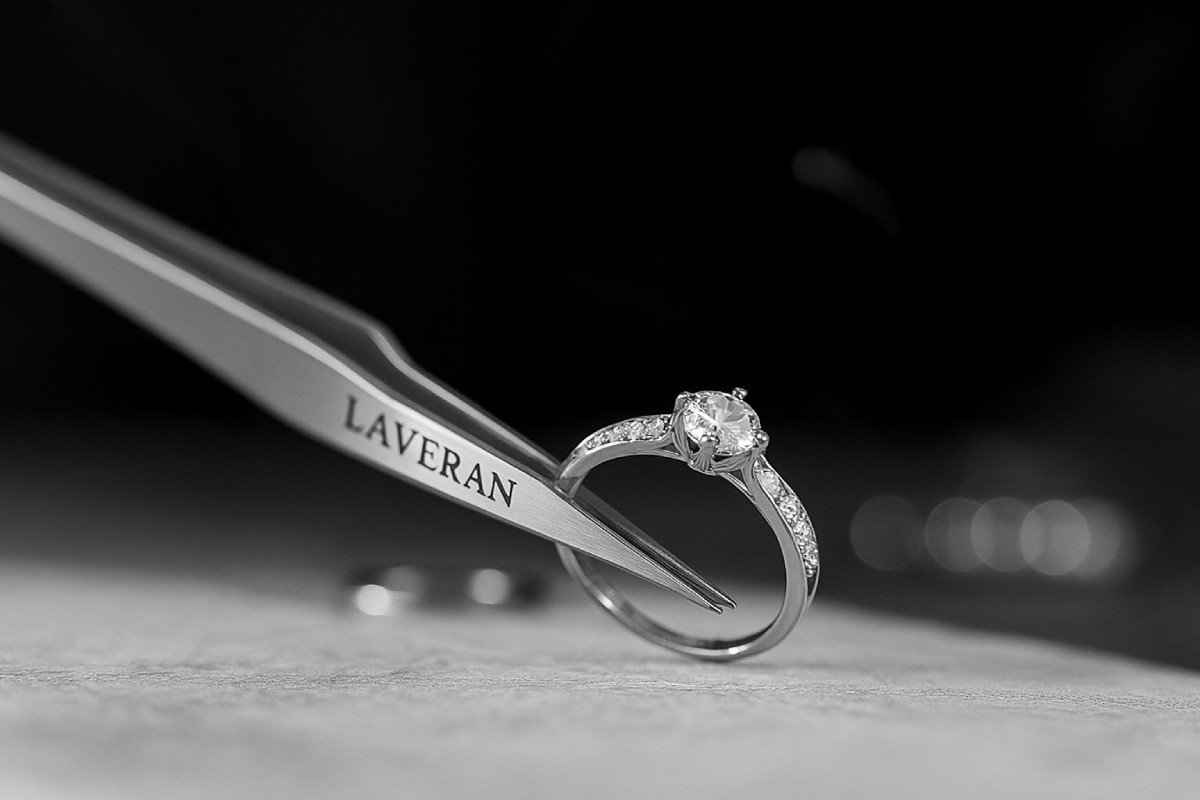 Vue macro d’une bague sertie d’un diamant de laboratoire, tenue par une pince gravée Laveran, illustrant le savoir-faire artisanal de la maison de haute joaillerie Laveran Paris.